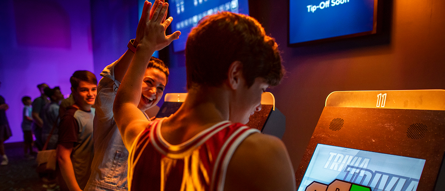 Two Guests high five while playing a touch screen trivia game at the NBA Experience venue in Disney Springs