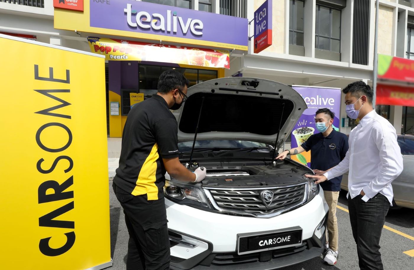 Cheng (centre) and Loo (right) watching a Carsome inspector checking out a SUV.