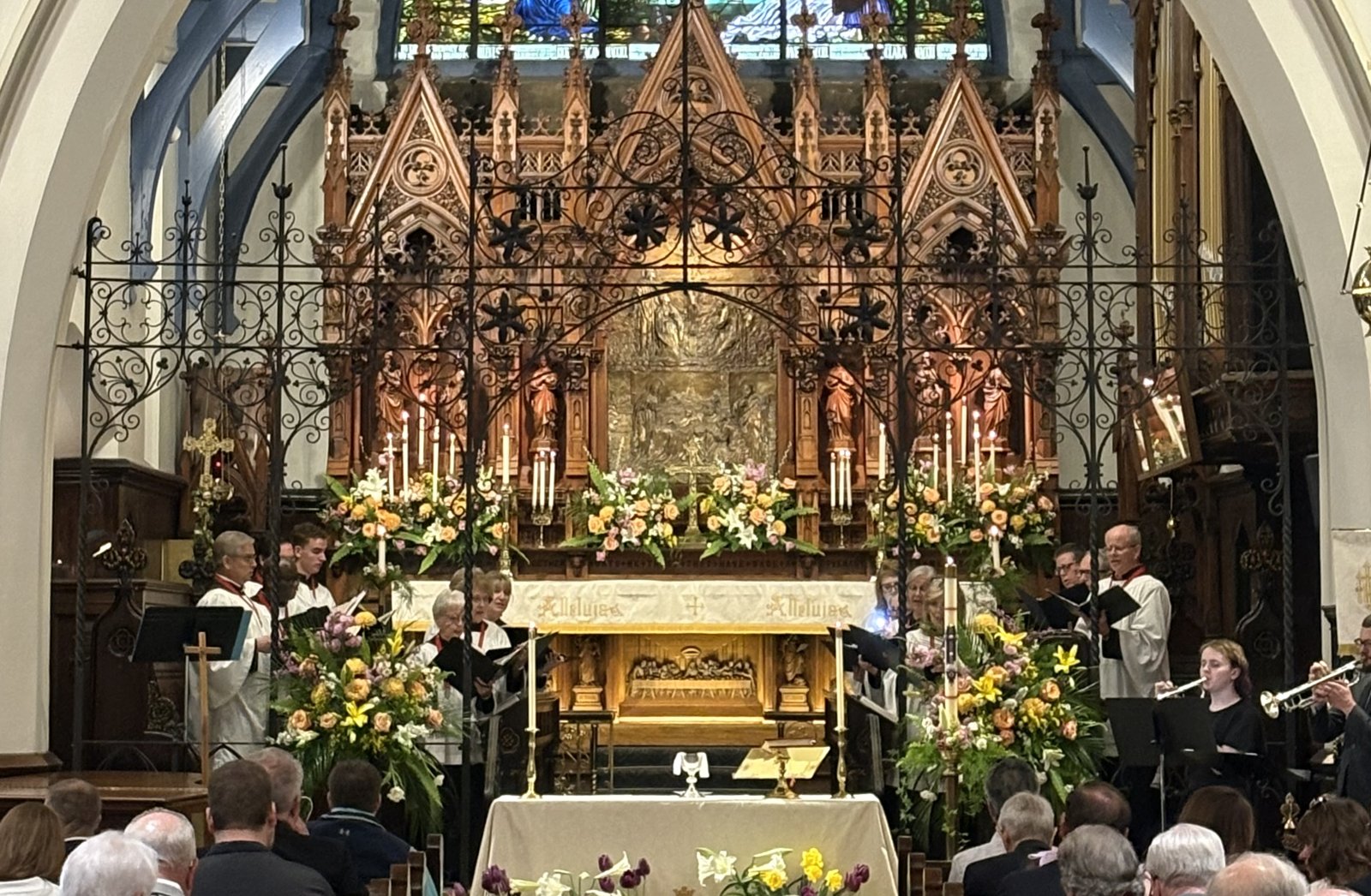 Saint John's choir and brass musicians leading Easter worship before the altar and reredos