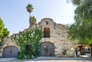 Mission style brick building with large curved wooden doors