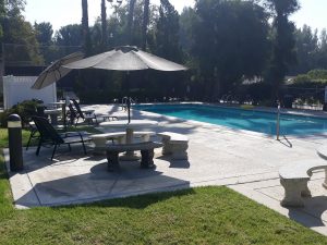 Large fenced pool with chairs and umbrellas