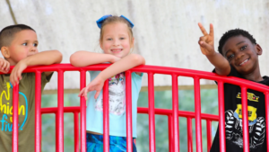 A group of three children having fun at a vibrant red playground