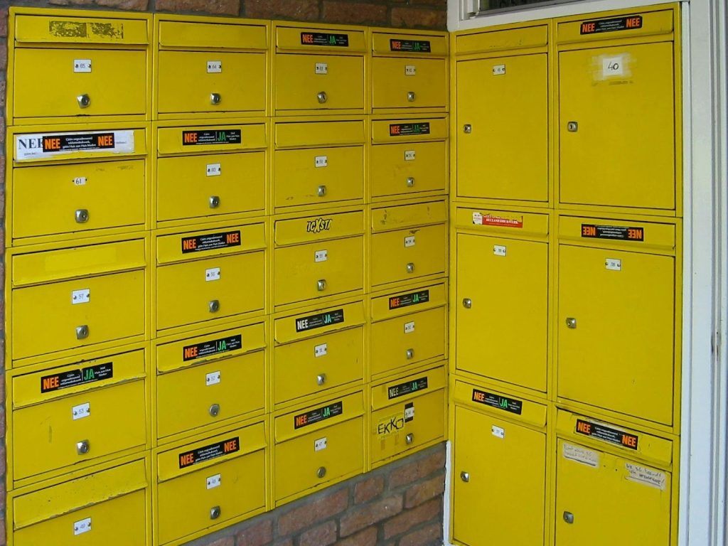 A wall of bright yellow mailboxes with small labeled compartments arranged in rows.
