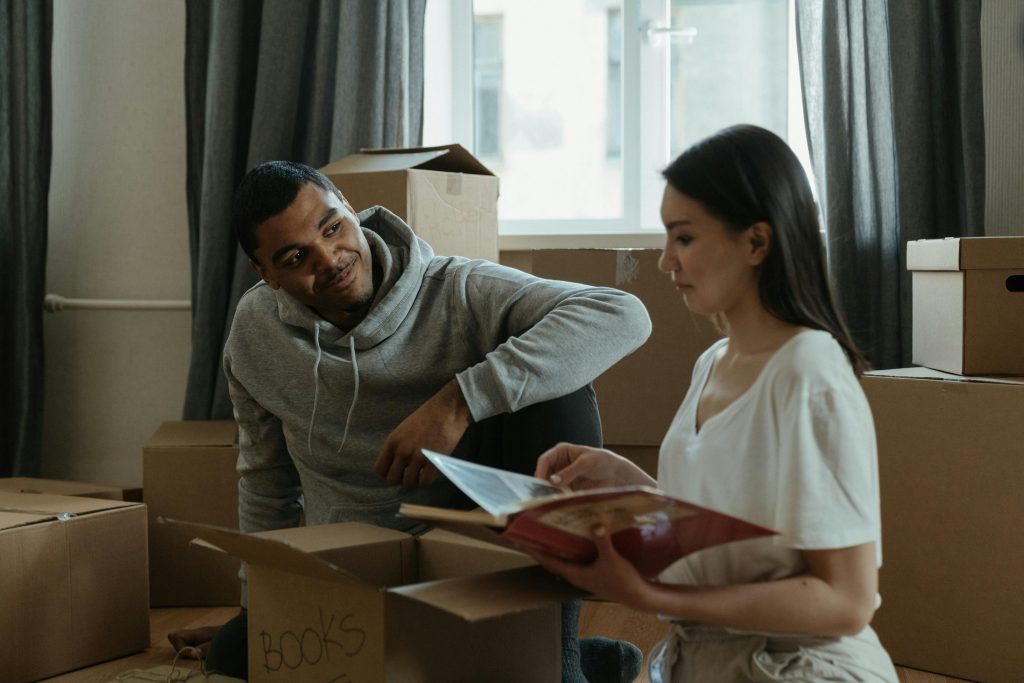 A couple exploring their new home while unpacking boxes and looking at albyum photo album