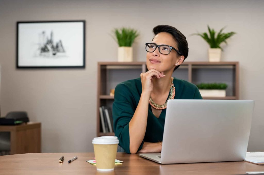 Woman sitting at laptop thinking.
