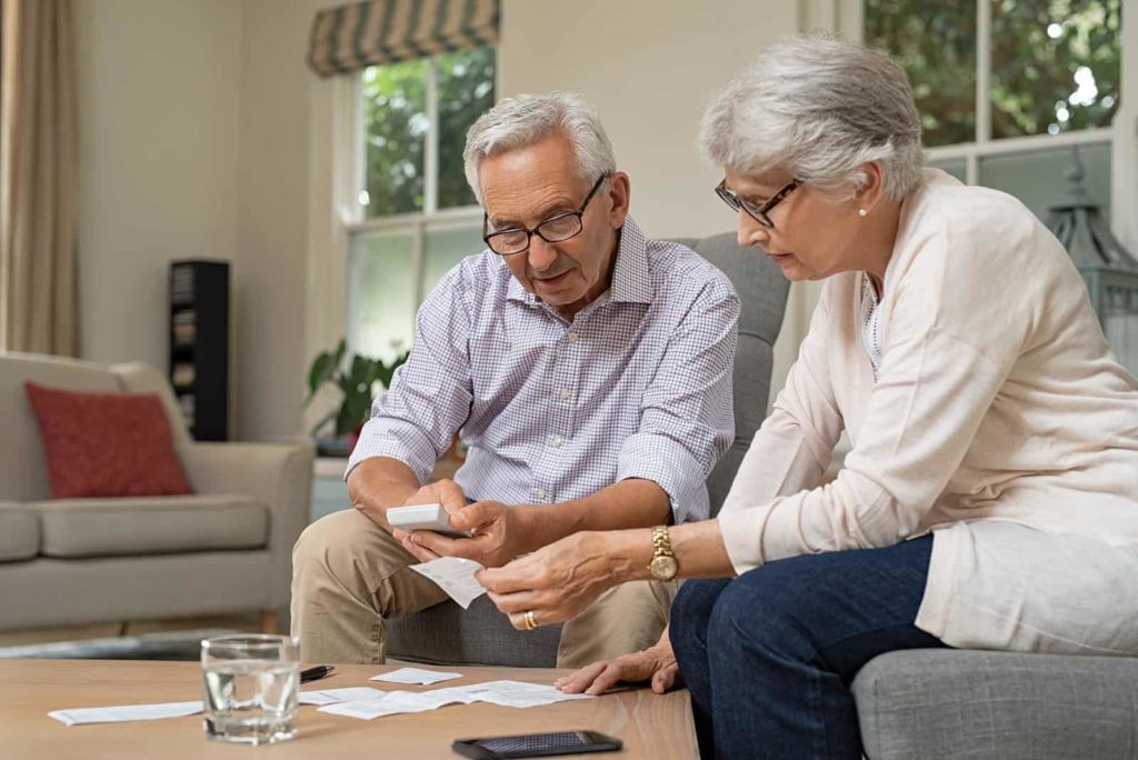 Smiling senior couple with papers, calculators and bills at home