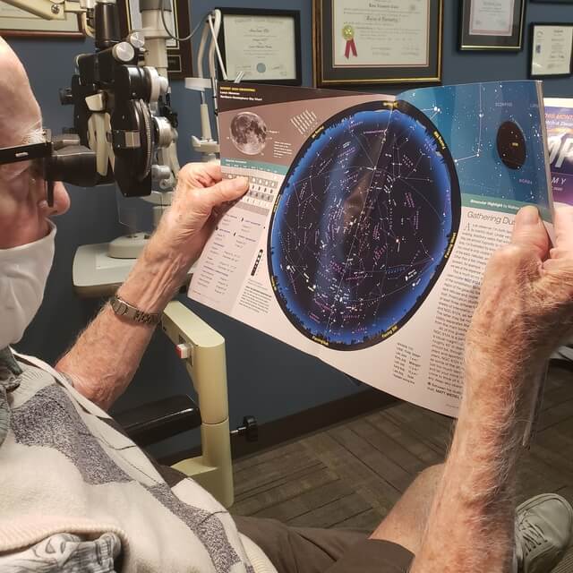 senior man reading using low vision glasses
