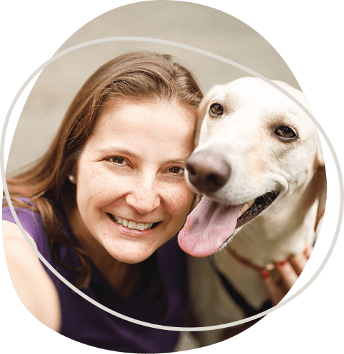 woman-smiling-while-holding-a-golden-retriever.png