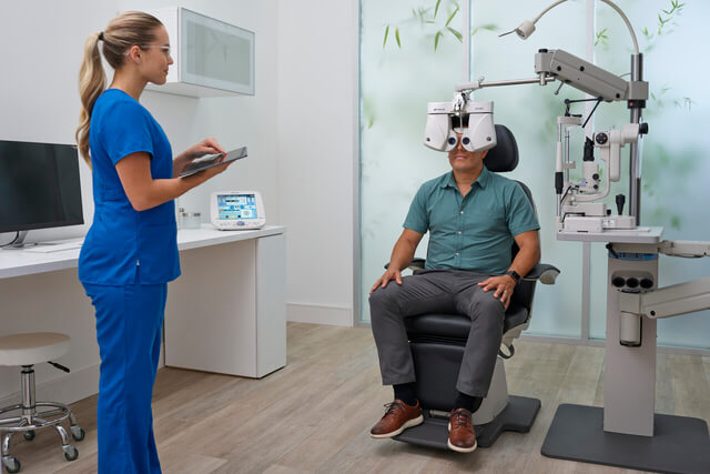 Woman enjoying eye exam, behind phoropter