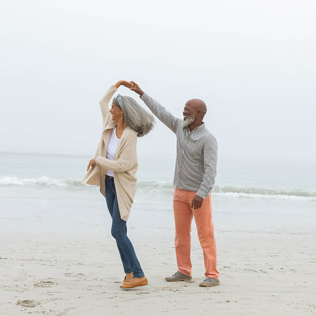 Front view of happy senior diverse Couple smiling at the beach.