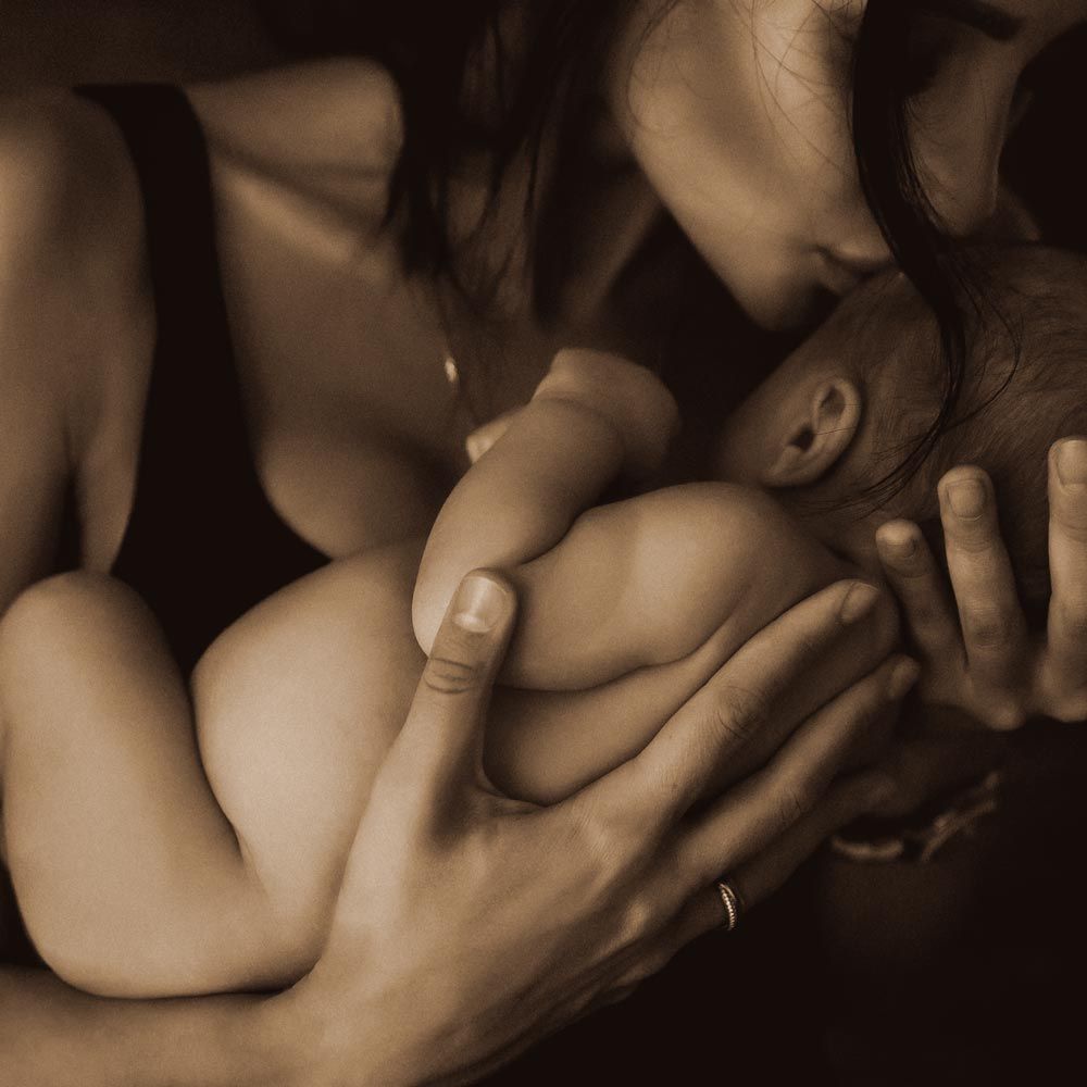 Mother in yellow and blue bikini lifting up laughing small child