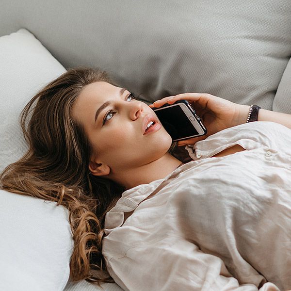 Woman lying on couch and talking on the phone