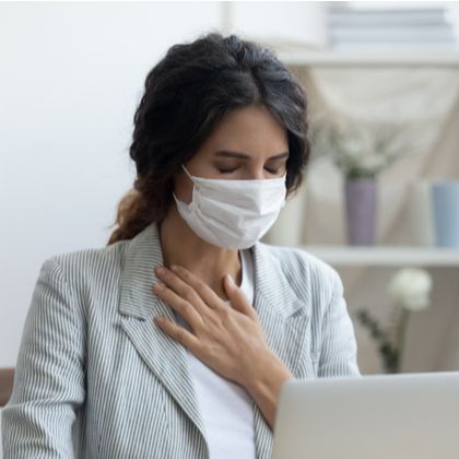 a masked woman with breathing difficulty holding her chest