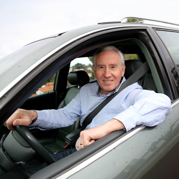An older man driving a car