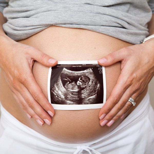 Woman holding ultrasound of baby over stomach