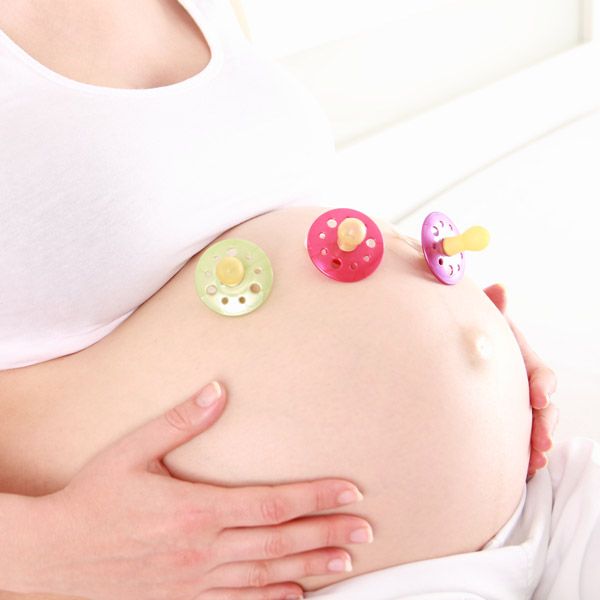 Woman with pacifiers on pregnant belly