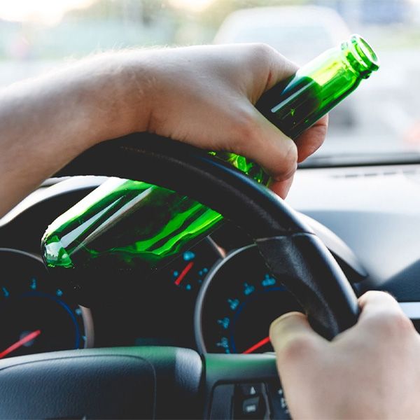 A person driving while drinking beer