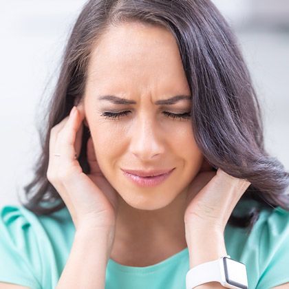 Woman holding hands to ears and grimacing