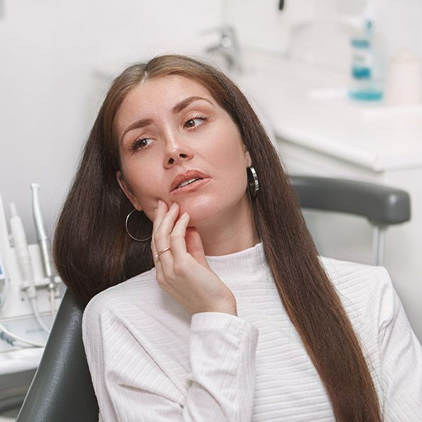 Woman in dental chair rubbing jaw