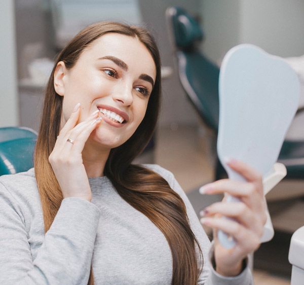 Smiling dental patient looking in mirror