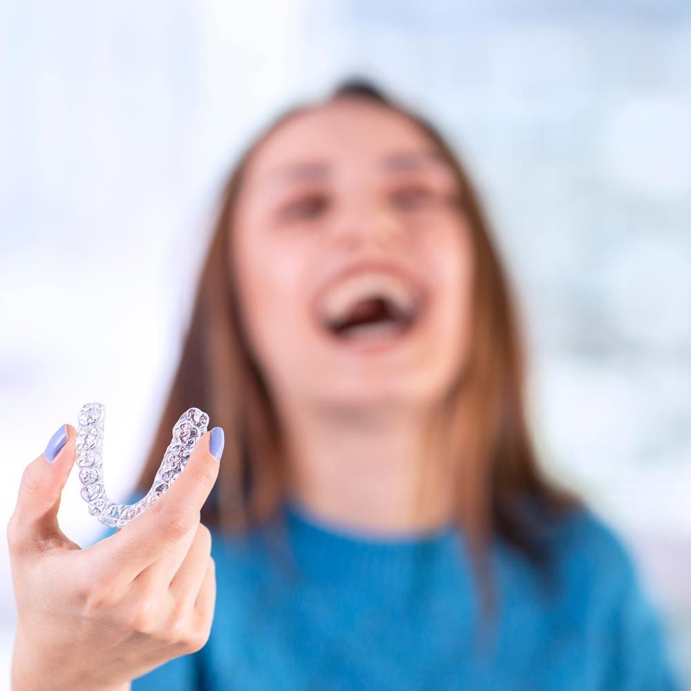 Woman laughing while holding Invisalign