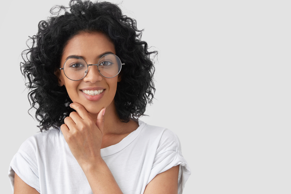 woman in glasses smiling with hand on her chin