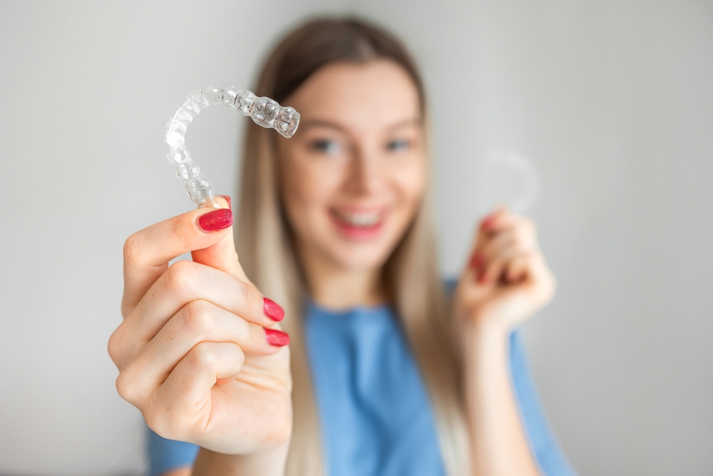 Woman holding two Invisalign aligners