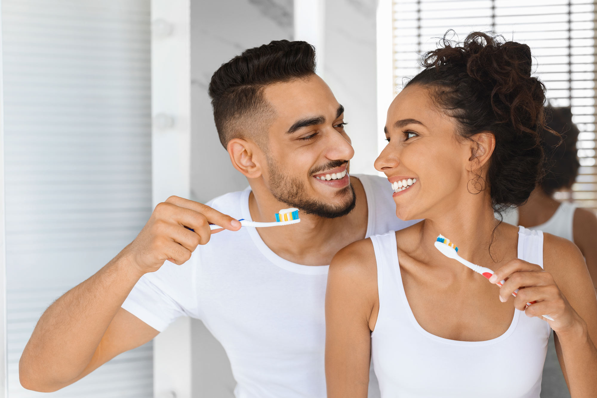 couple smiling while brushing their teeth