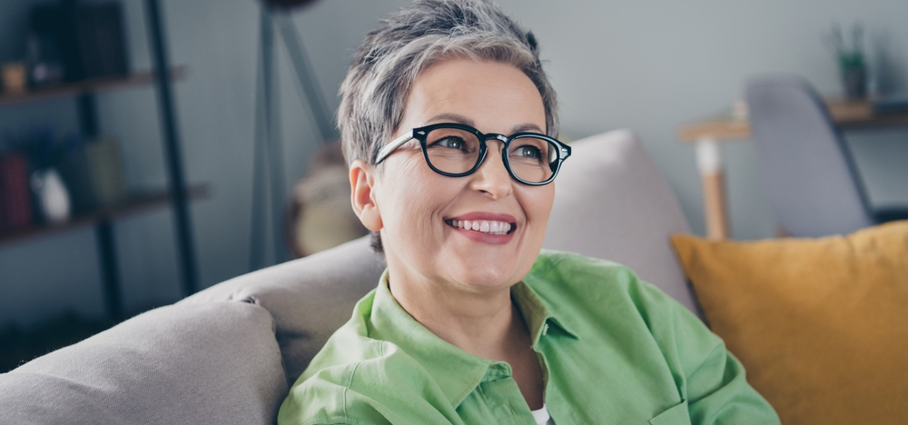 Woman with glasses smiling in her living room