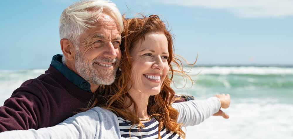 Older couple smiling while on the beach