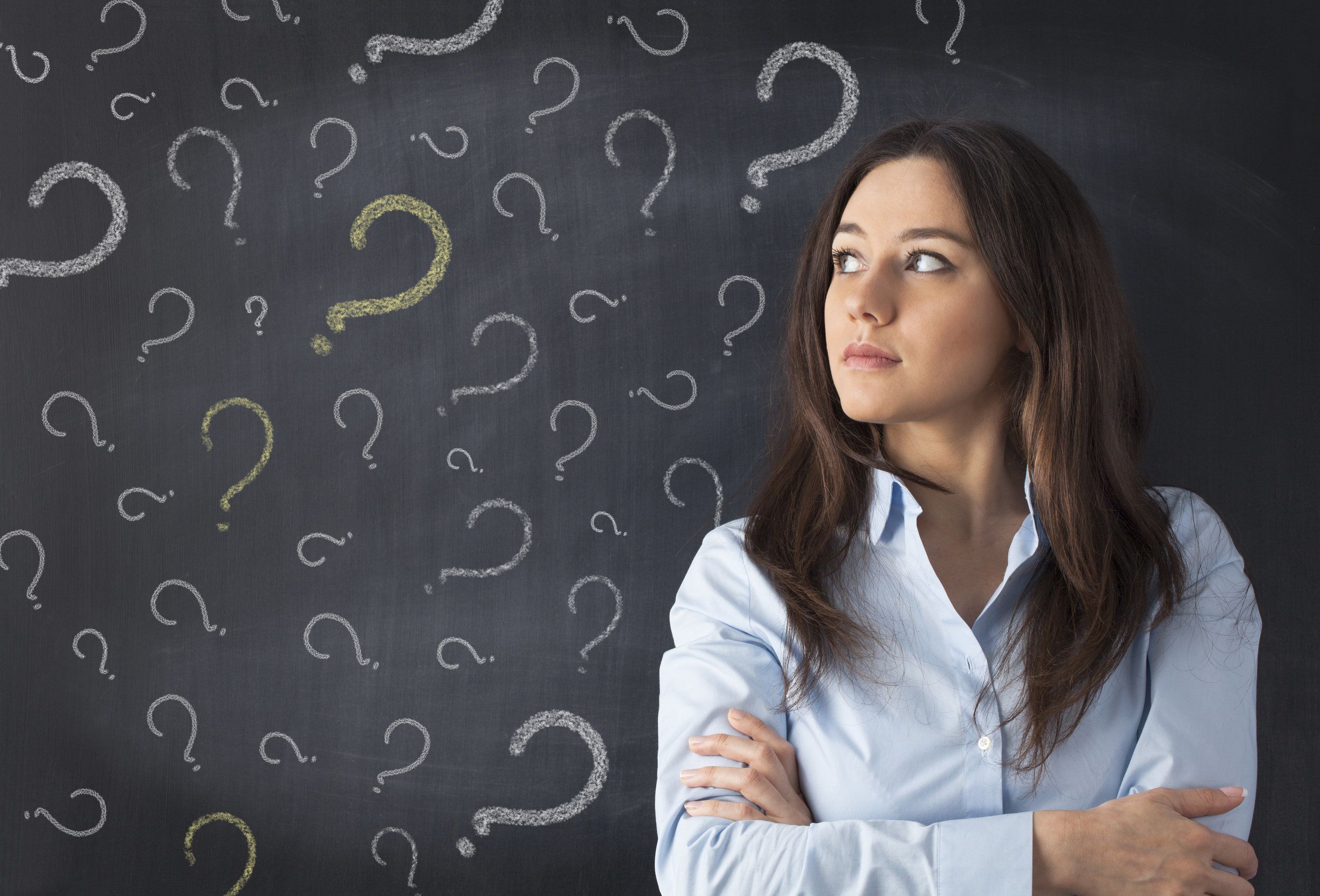 Woman in front of a blackboard full of question marks