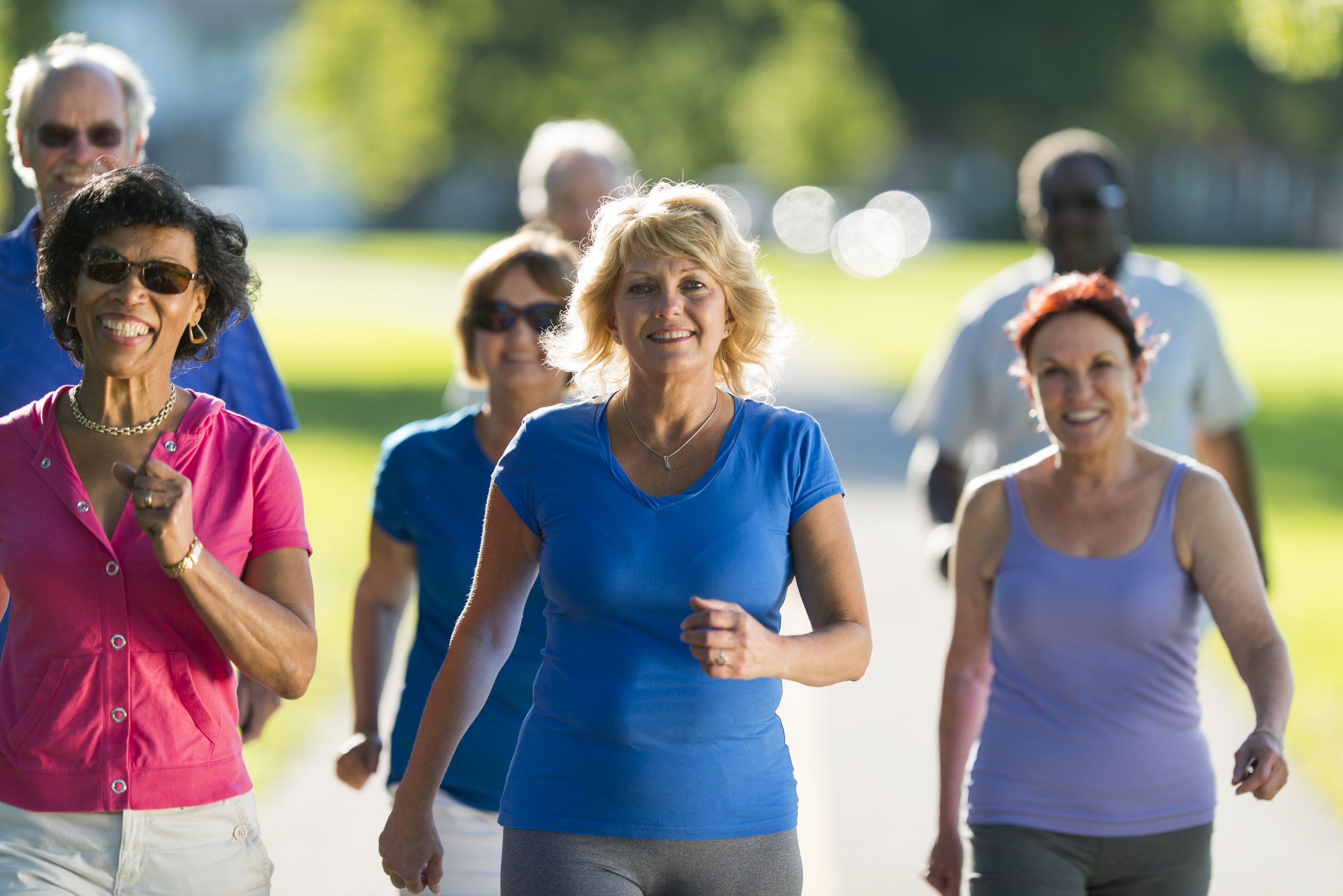 Smiling woman with implant-supported dentures walking with her friends