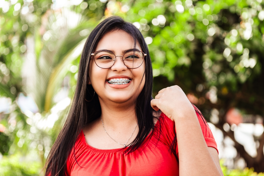 Young woman with braces smiling outside