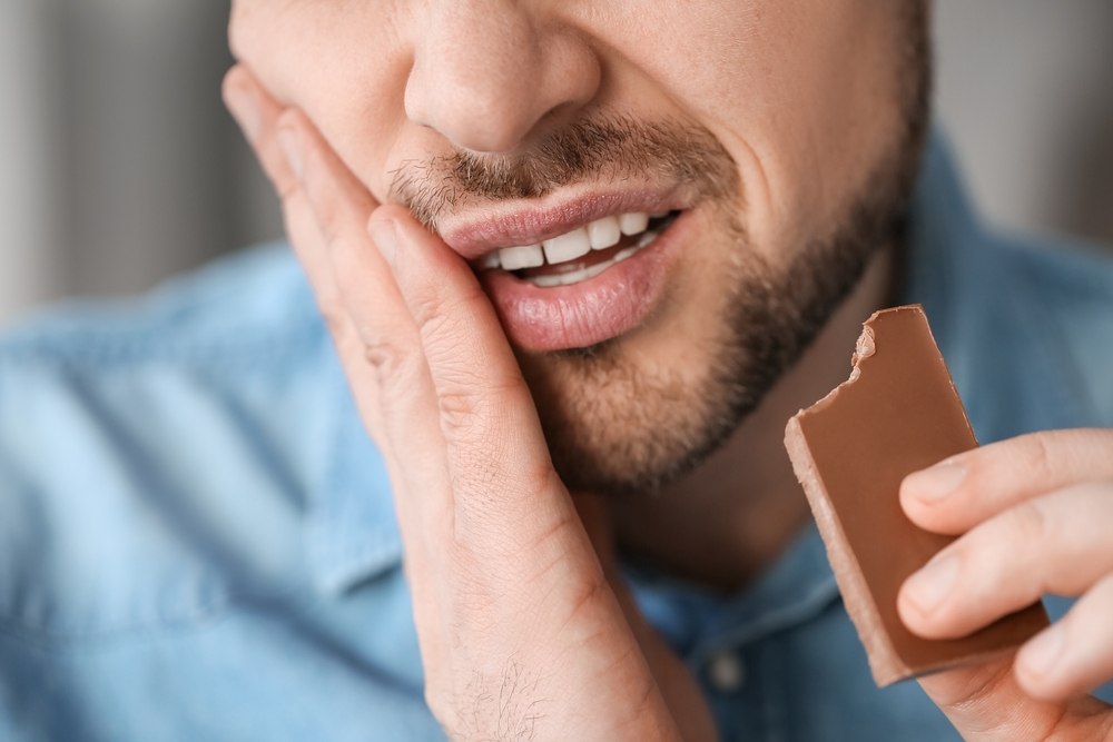 Man with sore tooth while having some chocolate
