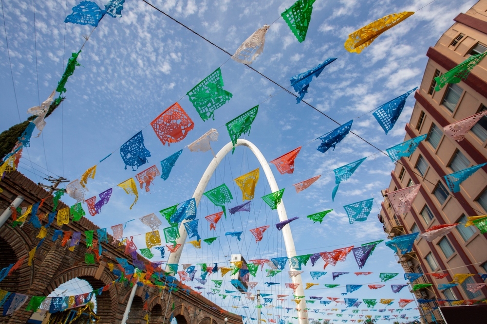 Papel picado decorations hanging between buildings in Mexico