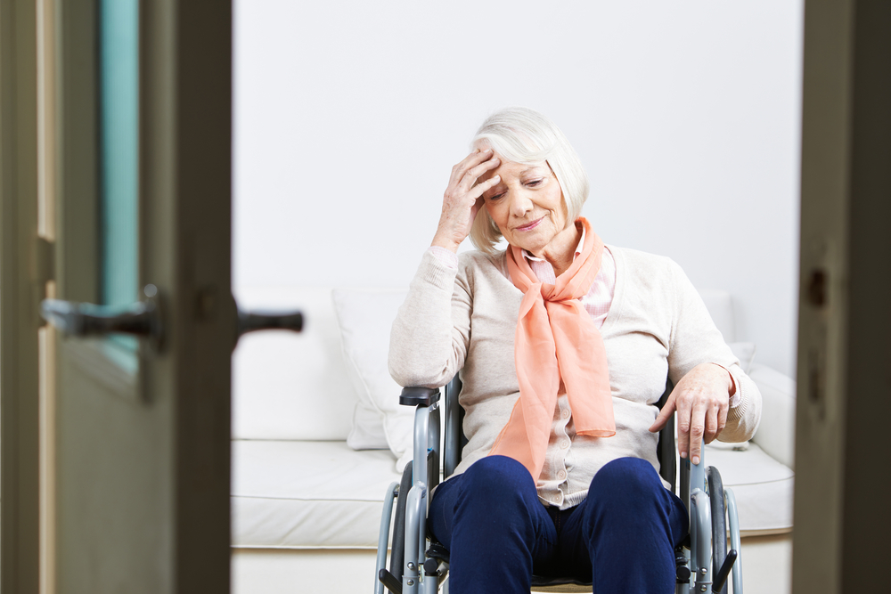 Elderly woman in a wheelchair alone in her room at a nursing home