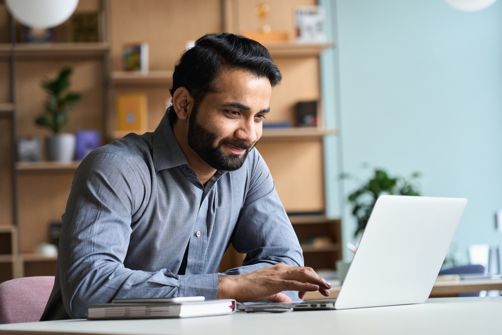 Man smiling while on his laptop at home