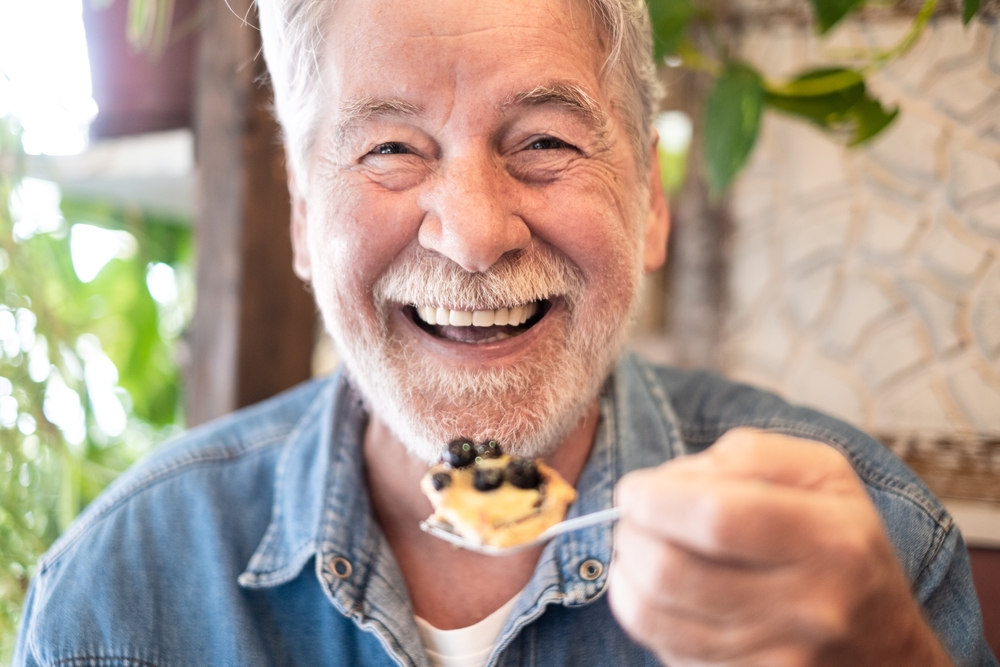 man smiling while eating breakfast