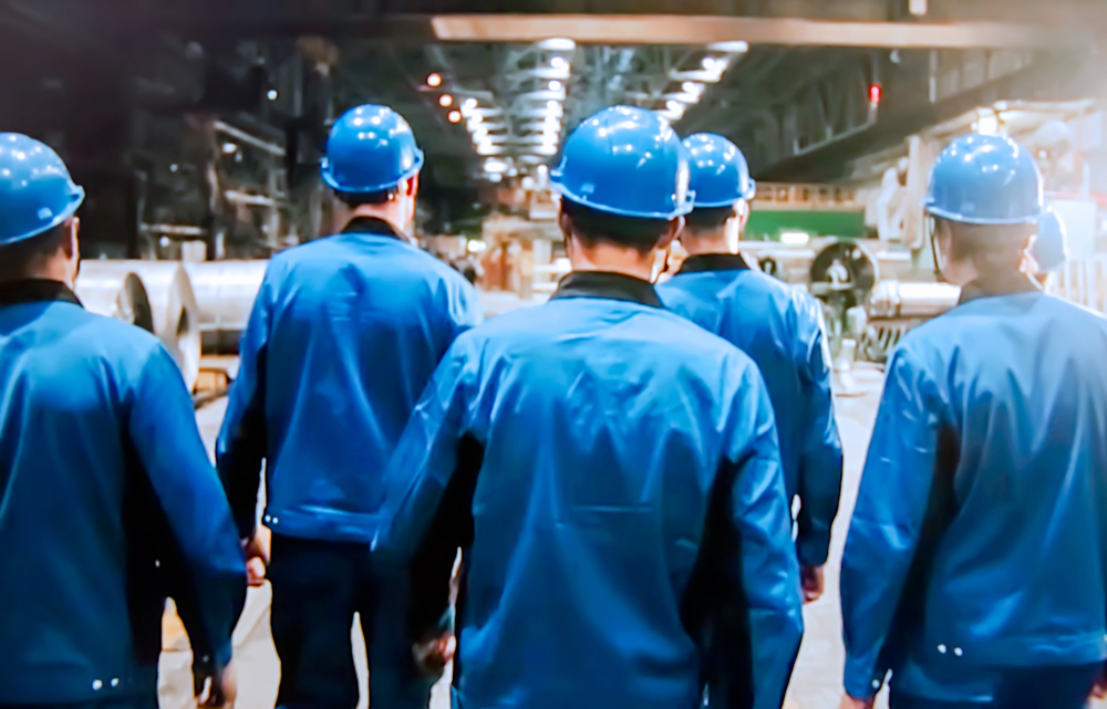 Factory workers standing together viewed from behind