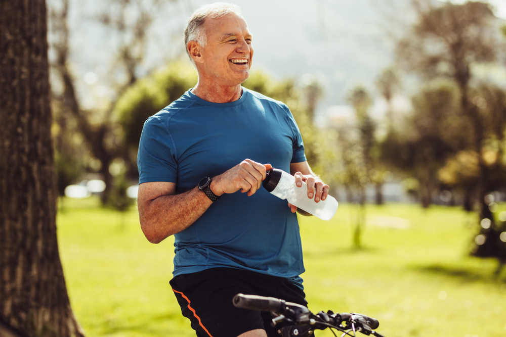 man smiling while drinking water and exercising