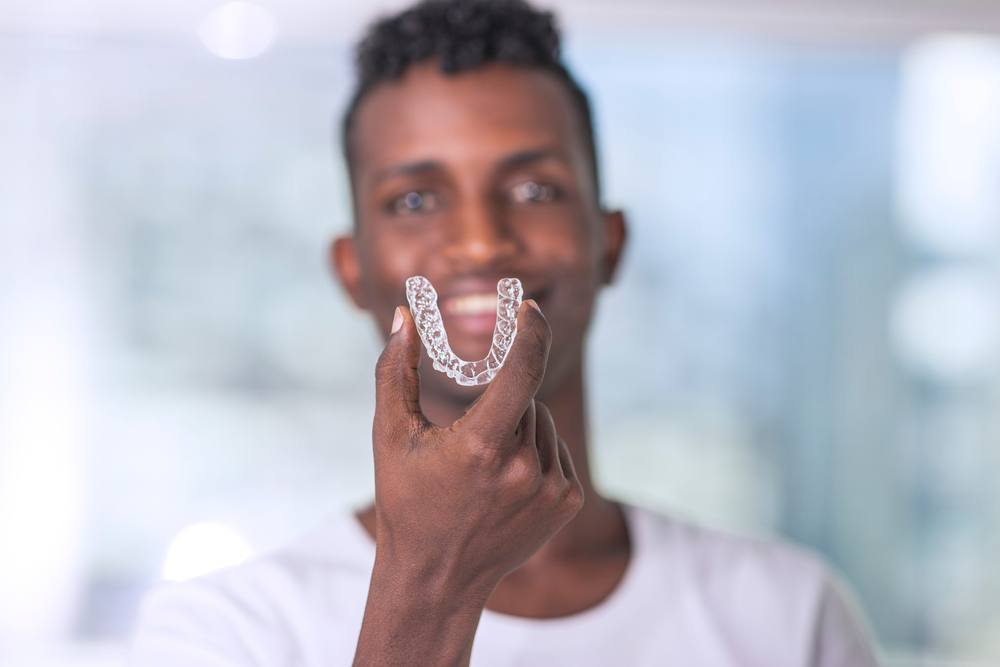 Young man holding Invisalign clear aligner