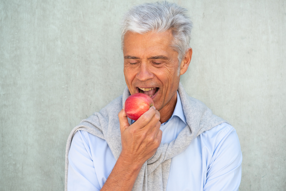 Elderly man about to bite into an apple