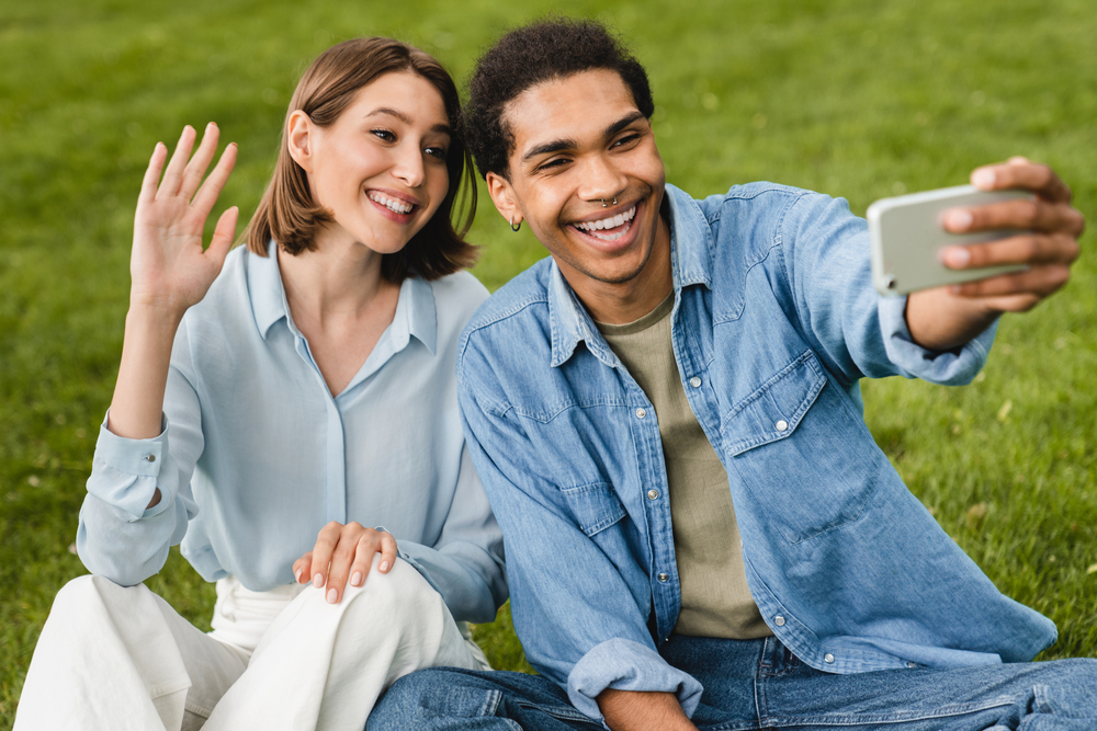 Young man and woman in the park taking a selfie together