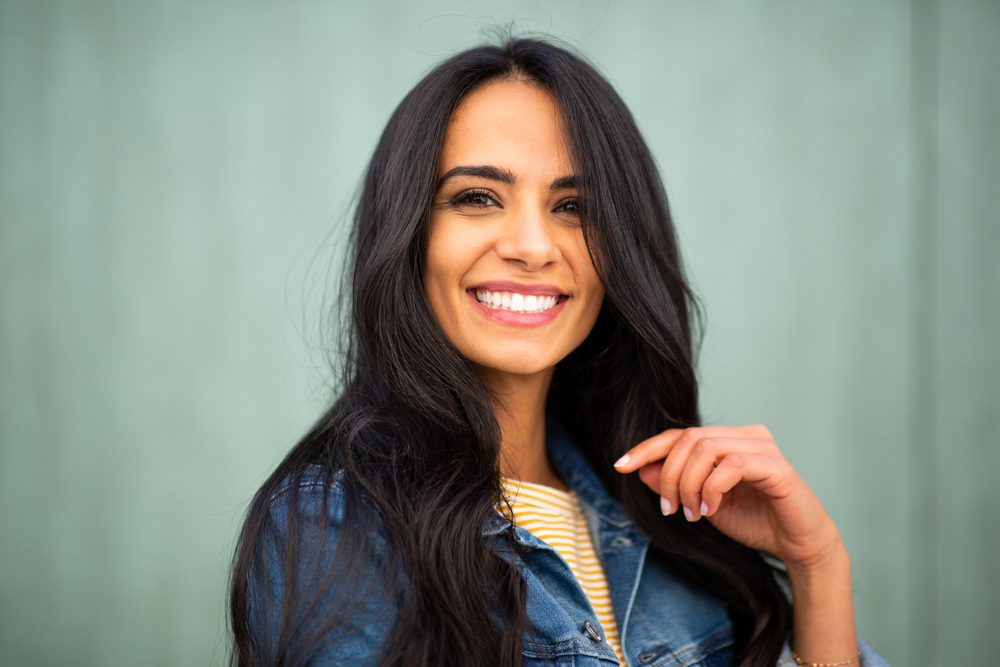 Young woman smiling in front of a green wall