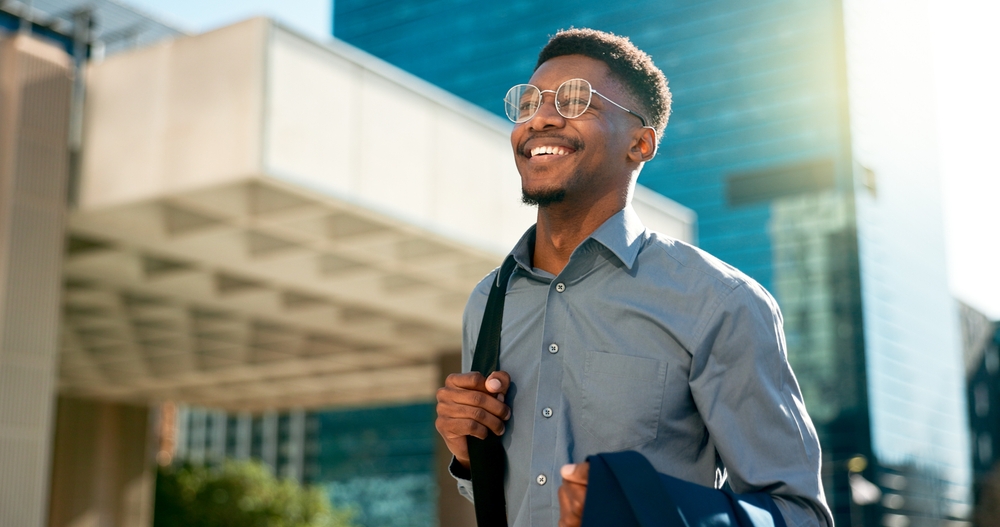 Young man with glasses smiling while he walks home from work