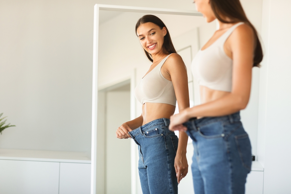 Woman looking at how loose her jeans are after losing a lot of weight