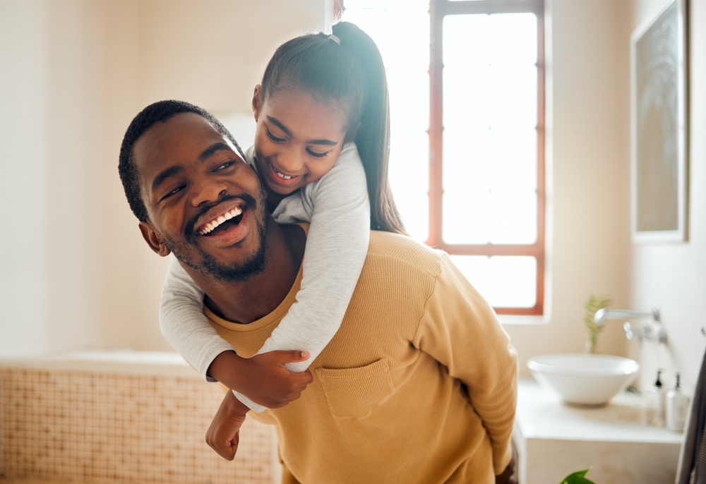 Father laughing while giving his daughter a piggyback ride