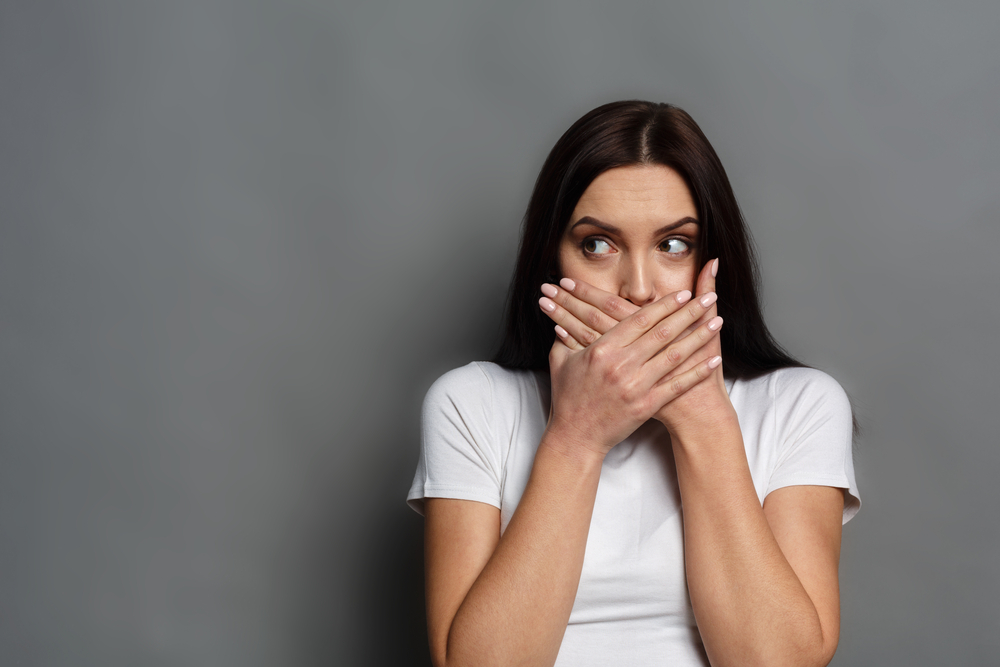 Anxious woman covering mouth with both hands