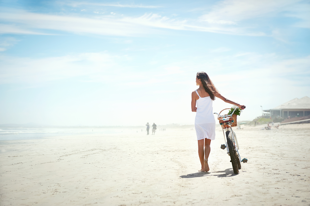 Woman walking her bicycle on the beach