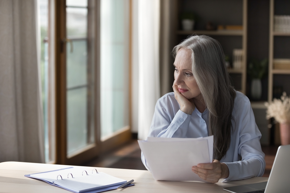 Worried woman looking at paperwork at her desk